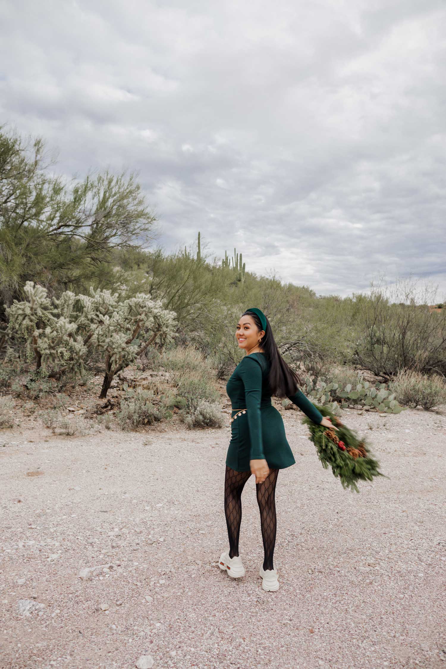 Molly larsen lifestyle blogger standing in a green dress holding a Christmas wreath in the Arizona desert Green Dress, Emerald Green Dress