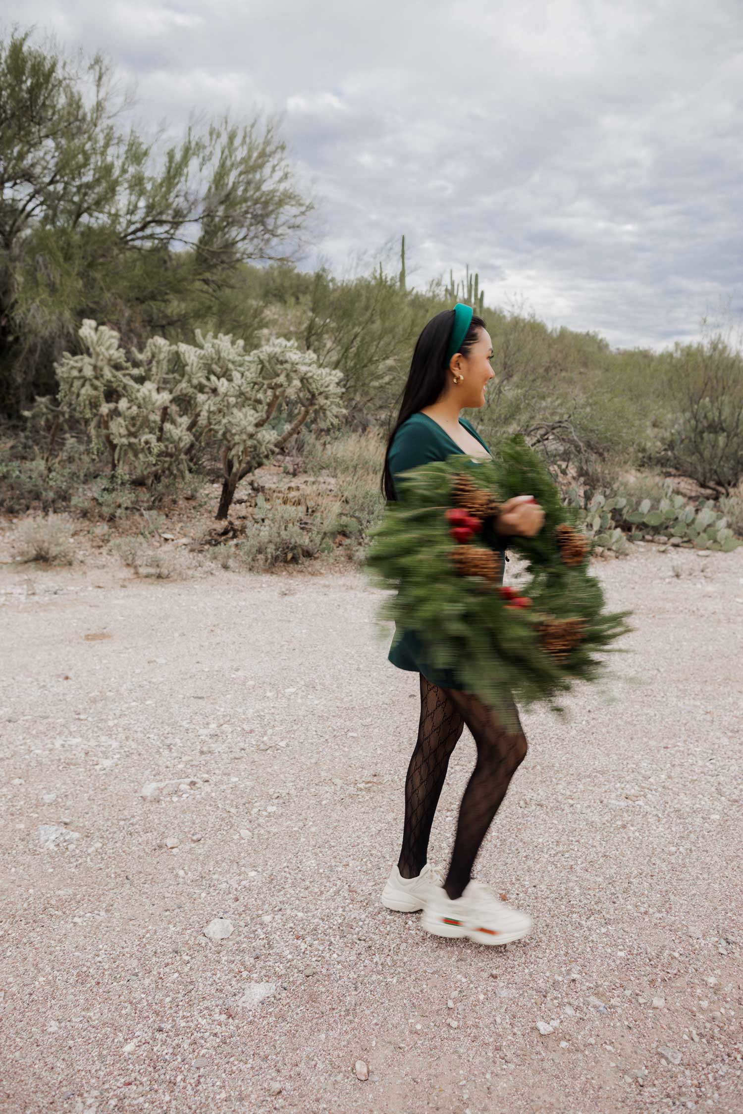 Molly larsen lifestyle blogger standing in a green dress holding a Christmas wreath in the Arizona desert Green Dress, Emerald Green Dress
