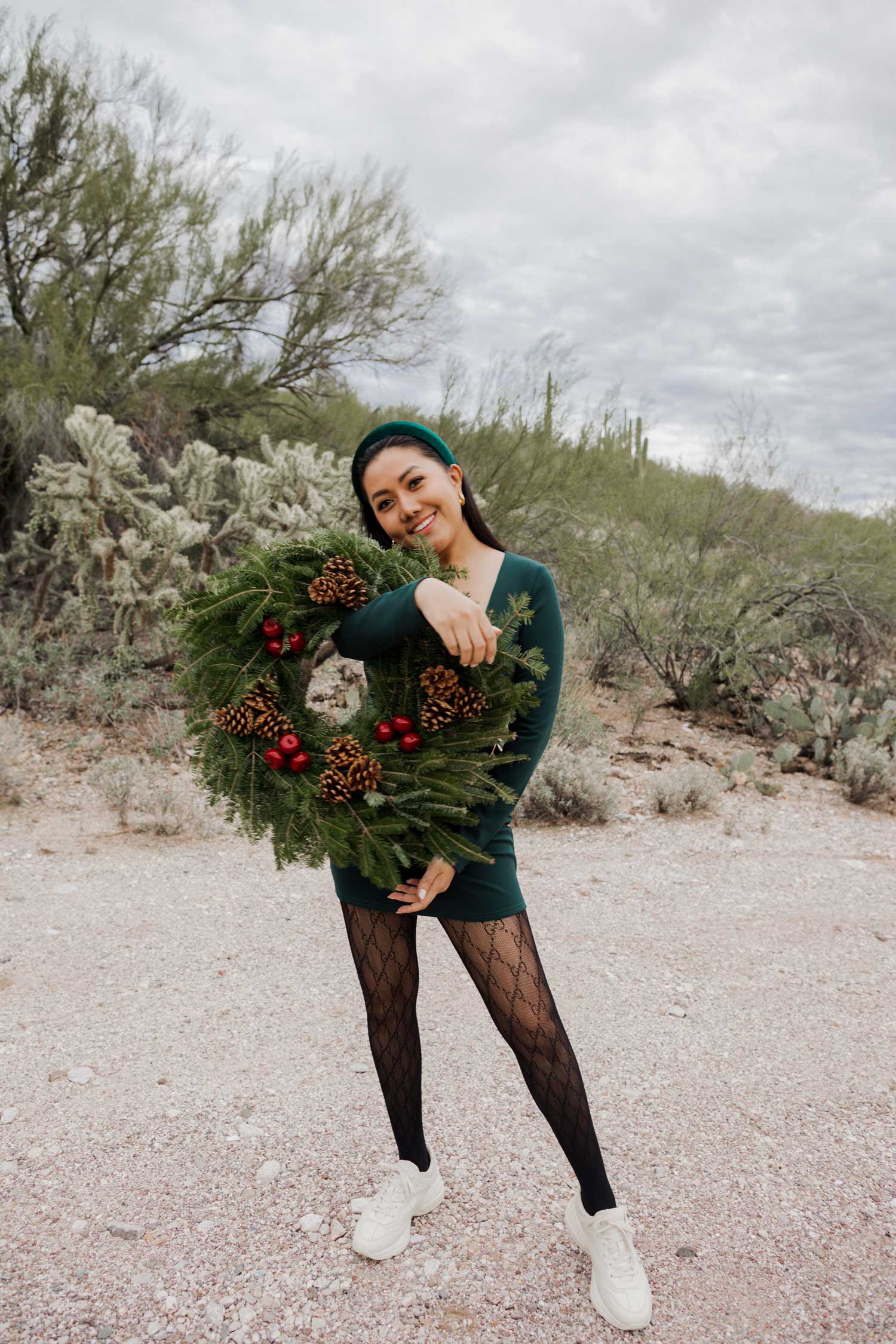 Molly larsen lifestyle blogger standing in a green dress holding a Christmas wreath in the Arizona desert Green Dress, Emerald Green Dress