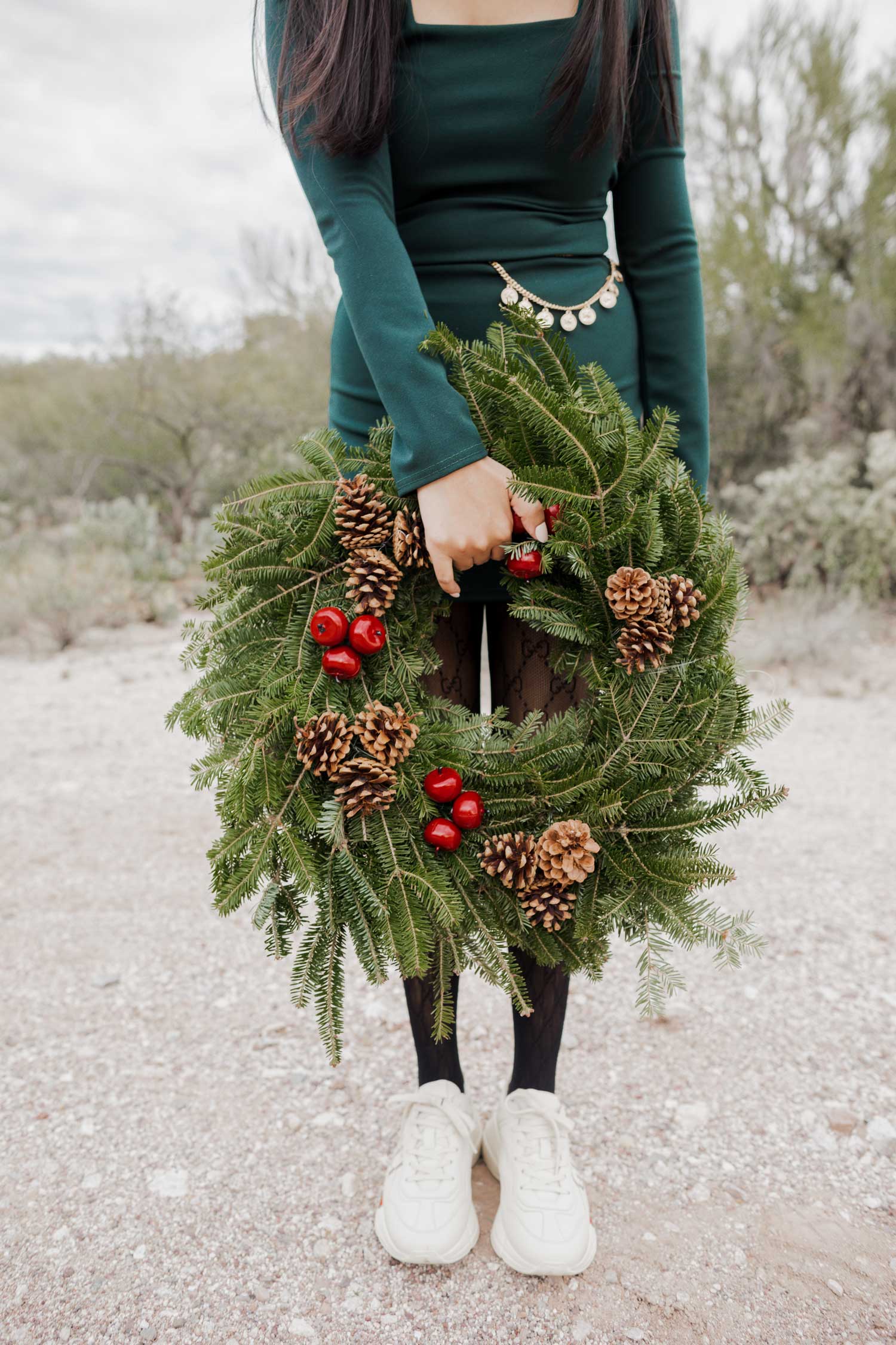 Molly larsen lifestyle blogger standing in a green dress holding a Christmas wreath in the Arizona desert Green Dress, Emerald Green Dress