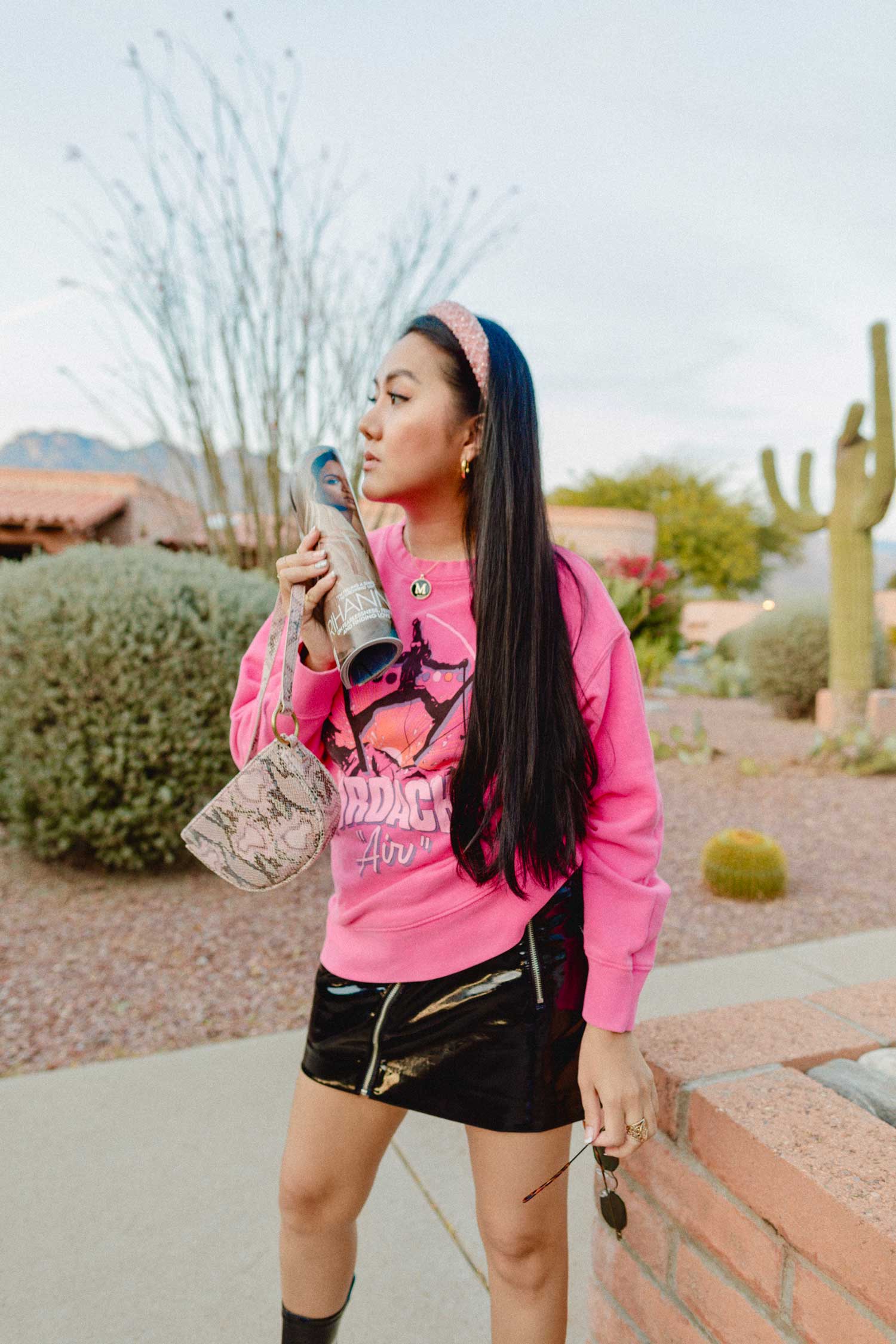 Molly Larsen lifestyle blogger standing in a pink top and black skirt holding a magazine and sunglasses and a magazine while wearing black boots Smart goals 2020 goals what are smart goals