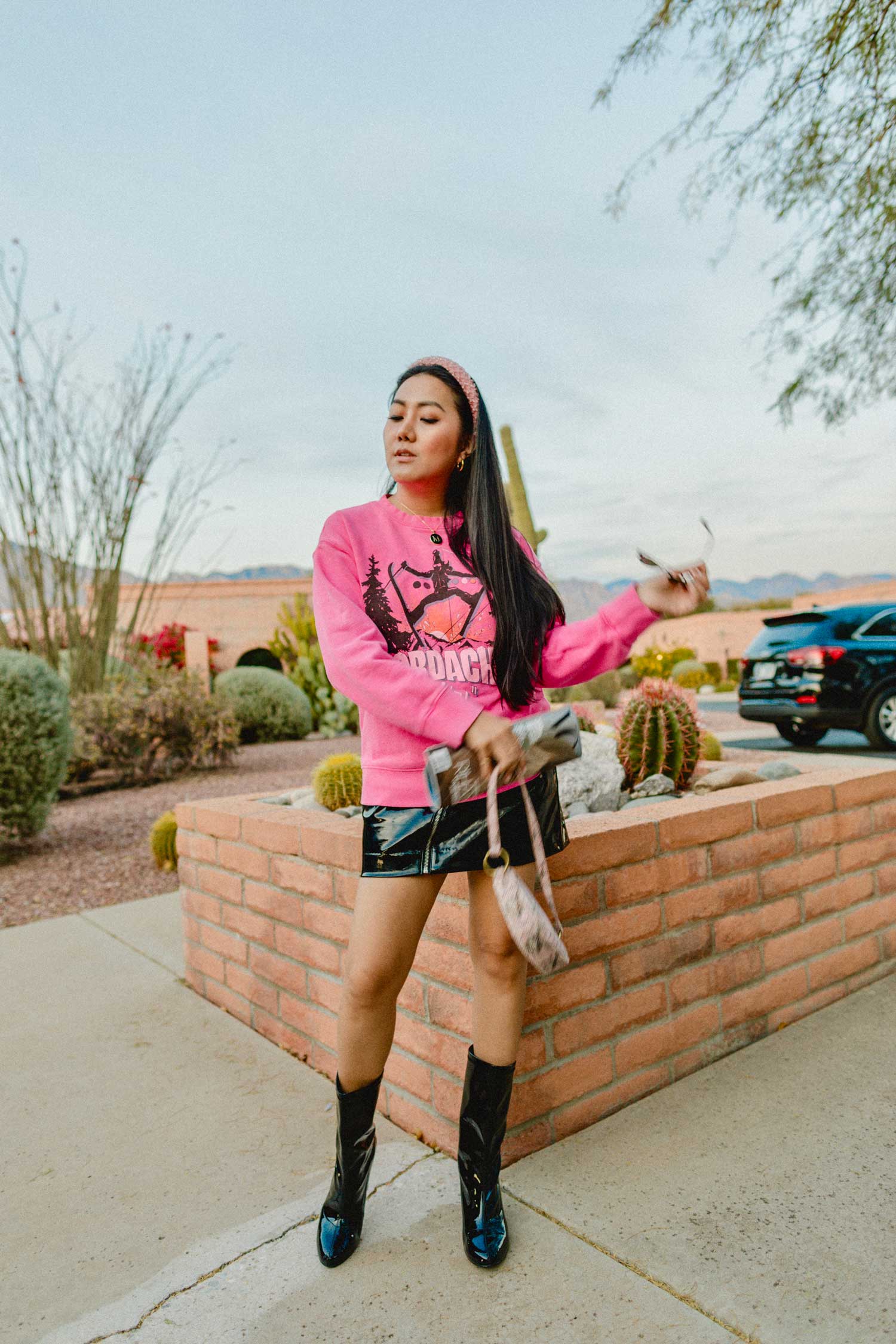 Molly Larsen lifestyle blogger standing in a pink top and black skirt holding a magazine and sunglasses and a magazine while wearing black boots Smart goals 2020 goals what are smart goals